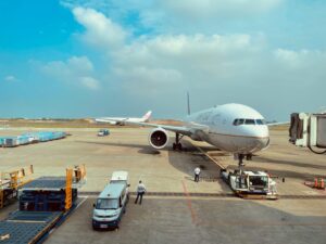 Boeing 777 airplane at Taiwan's Taoyuan International Airport gate with ground crew preparing for departure.