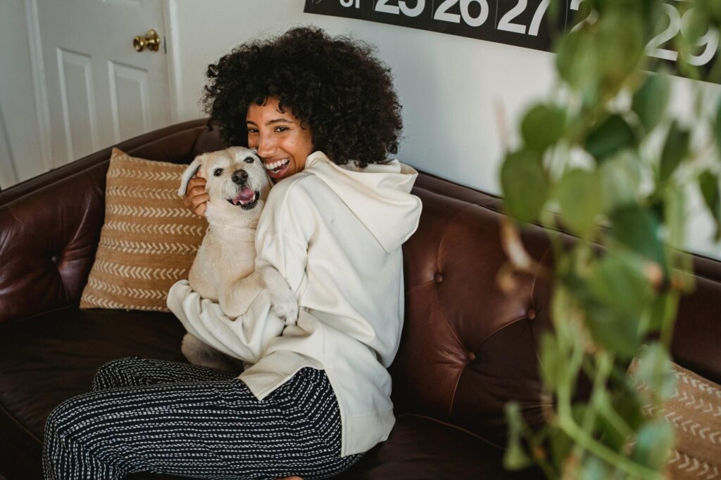 A happy woman embraces her dog on a comfortable sofa, enjoying a relaxing day at home.